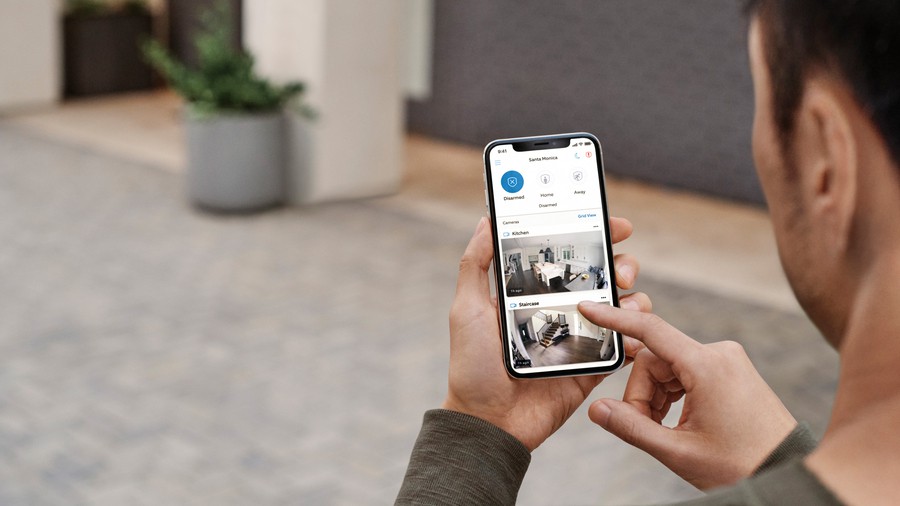 Man views his Ring cellphone app, browsing surveillance camera feeds from somewhere other than his home