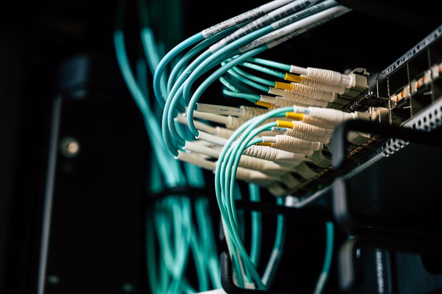 Close-up of teal network cables plugged into a data server or switch, illustrating structured wiring in a professional IT setup.